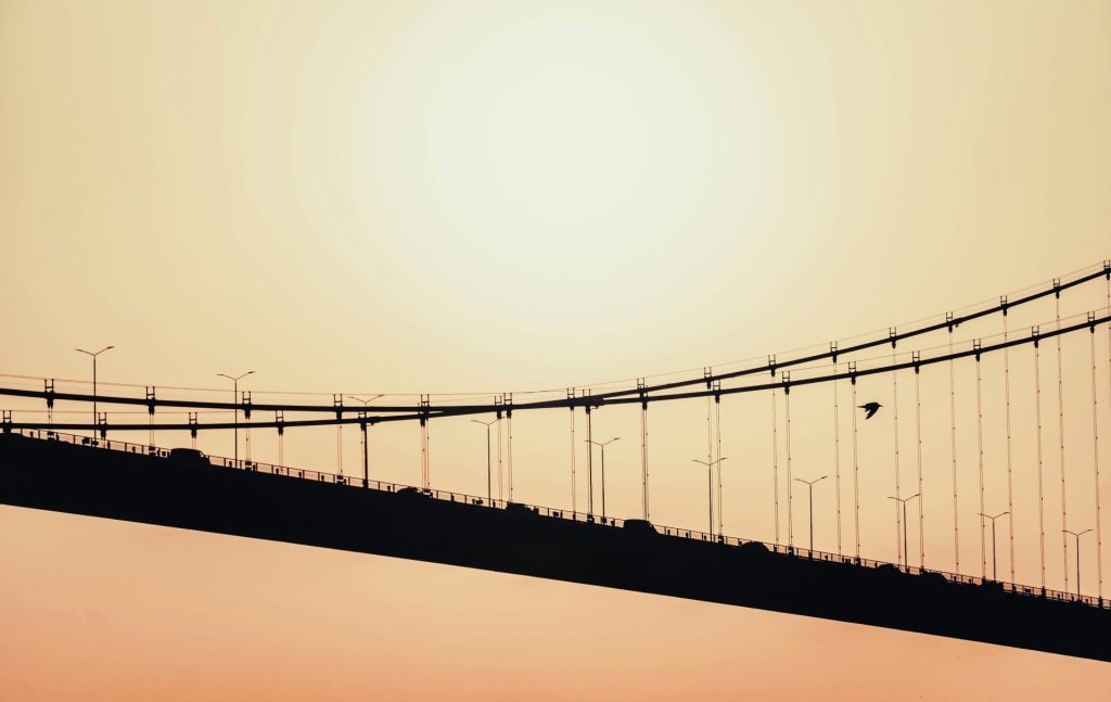 A long bridge with a plane flying over it